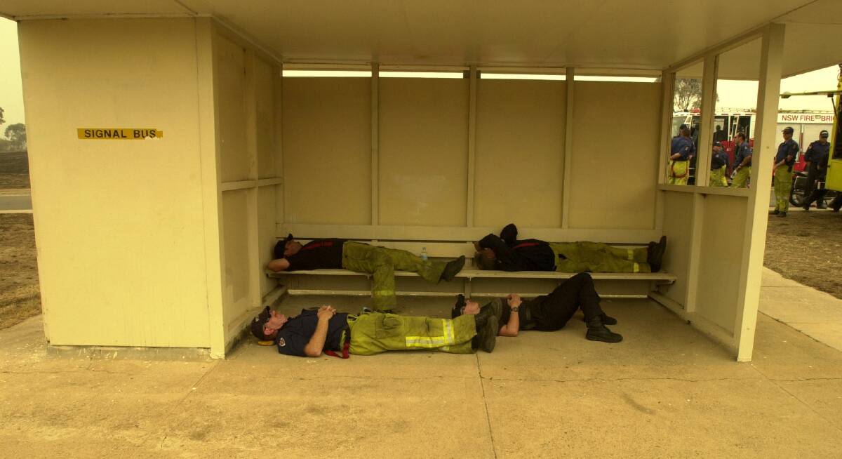 Firefighters catch up on some rest in a bus shelter in Hindmarsh Drive in Duffy on Monday, January 20, 2003.  Photo: Richard Briggs 