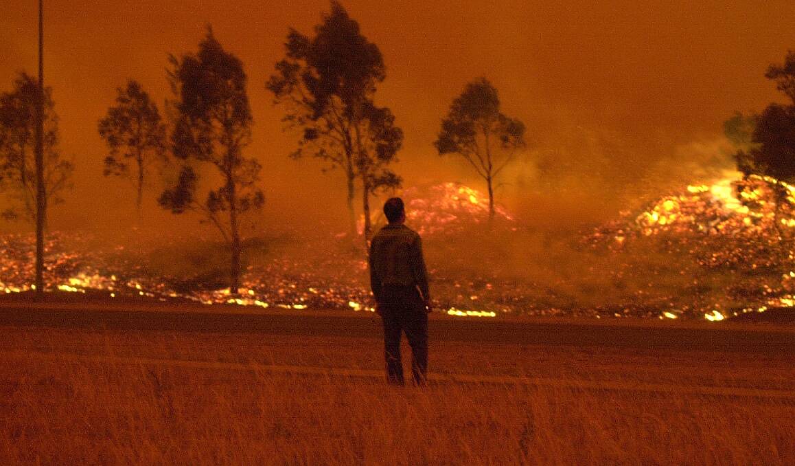 A resident watches grassland burn in Gordon on Saturday, January 18, 2003. Photo: Lannon Harley