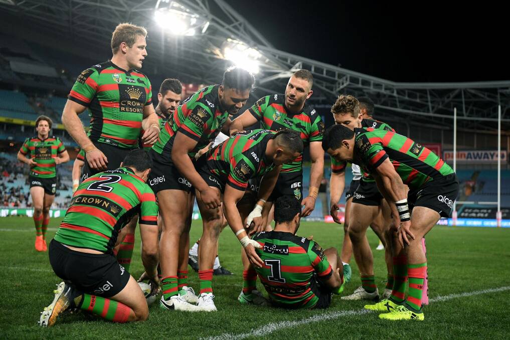 Concerned: Souths players gather around Johnston after he injured himself scoring his third try. Photo: AAP