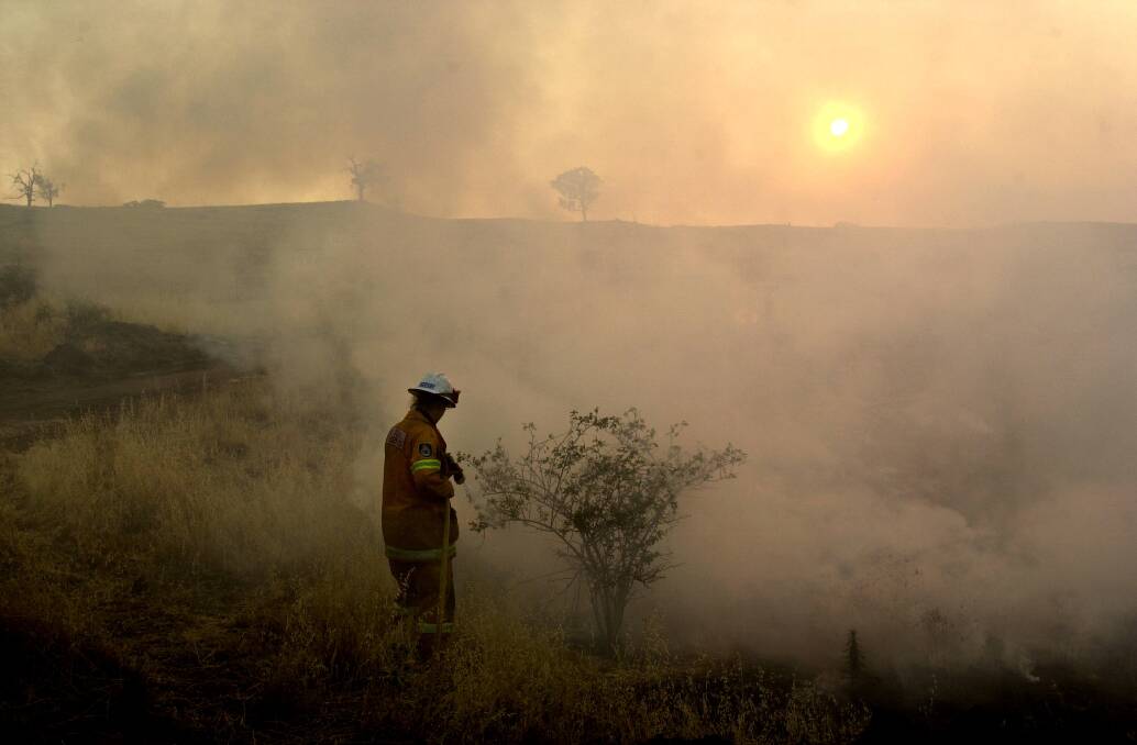 Rural firefighter Rhianna Sneesby from Tuncurry mops up a grass fire just after dawn near Holt on Sunday, January 19, 2003. Photo: Lannon Harley