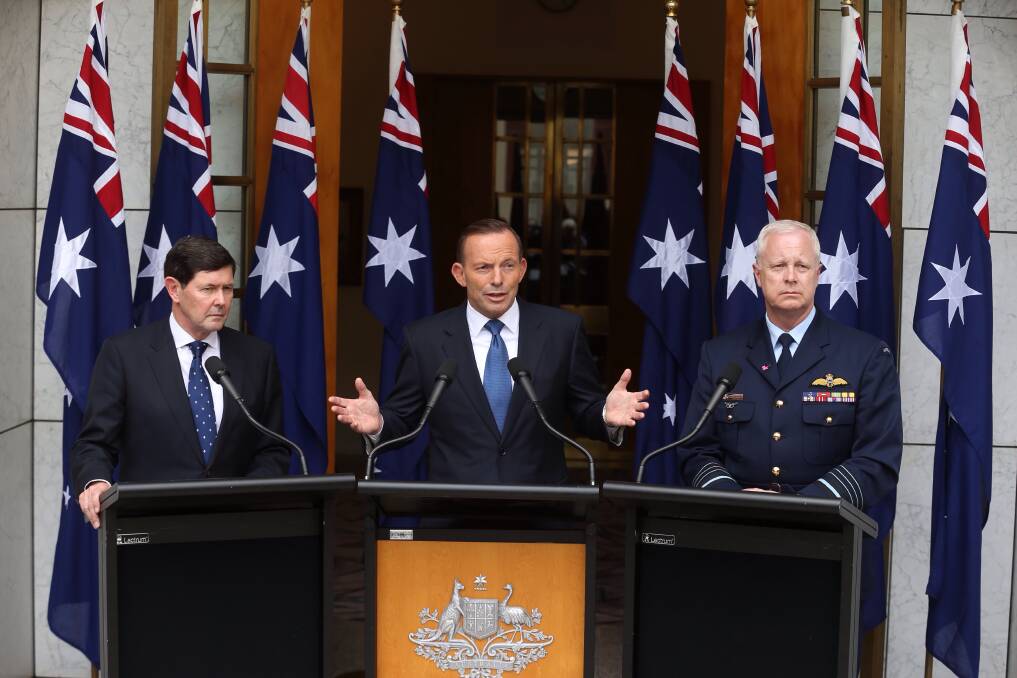 Then-prime minister Tony Abbott in 2015 announcing preparation for a troop deployment to Iraq. He is joined by then-Defence Minister Kevin Andrews and former Defence Force chief Air Chief Marshal Mark Binskin, and a number of national flags. Photo: Andrew Meares
