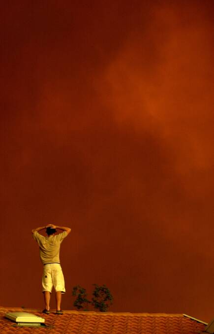 A residents watches the approaching red smoke from fires at Tharwa on January 18, 2003. Photo: Lannon Harley