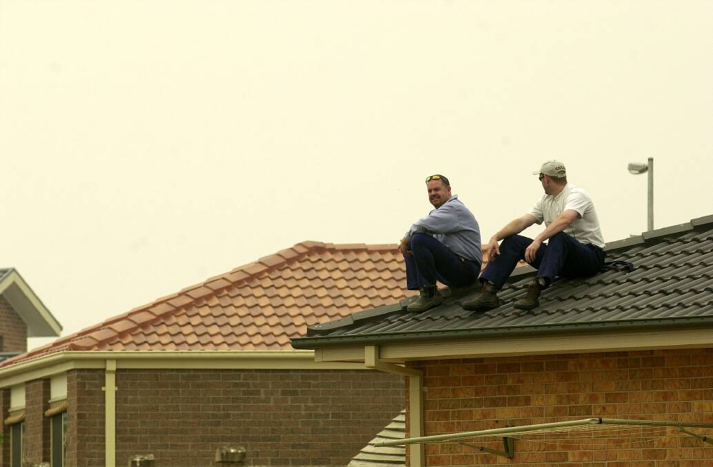 The Armour brothers Mick and Warren sits on their roof on Fairlight street in Dunlop awaiting news of approaching fires during a state of high alert on January 21, 2003. Photo: Lannon Harley
