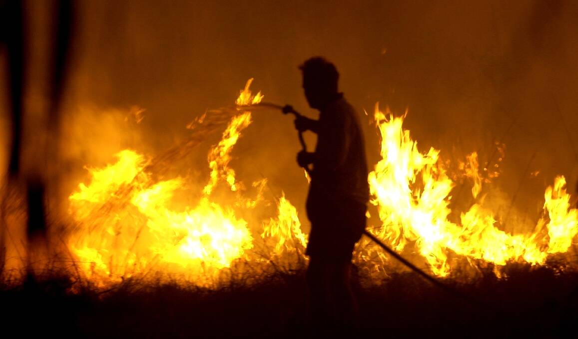 A resident fights an approaching bush fire with a hose during the 2003 Canberra bushfire. Photo: Lannon Harley