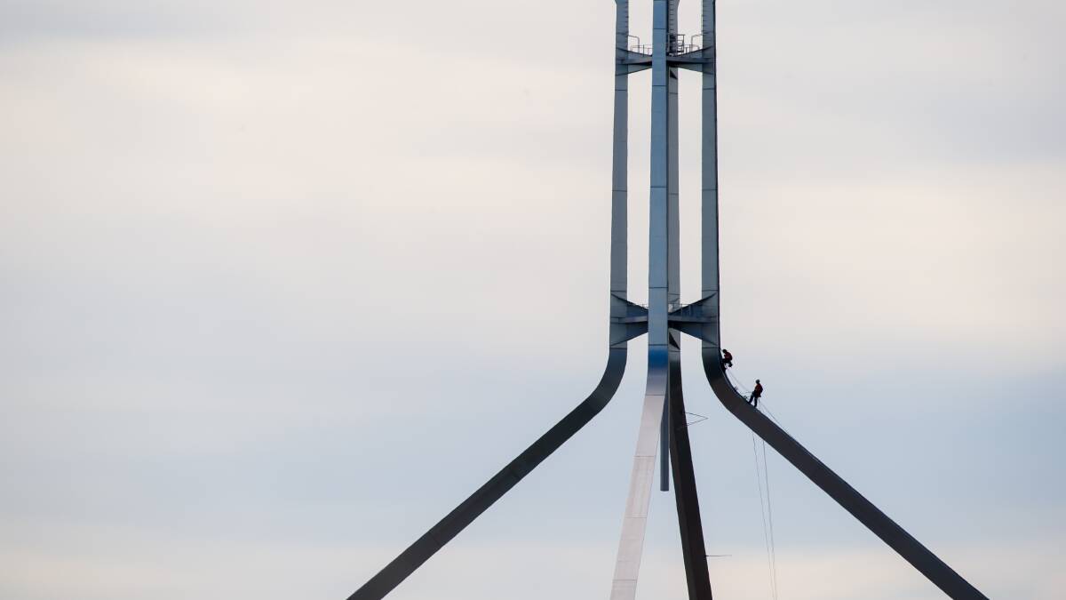 Industrial climbers scale the flag pole at Parliament House . Picture by Elesa Kurtz
