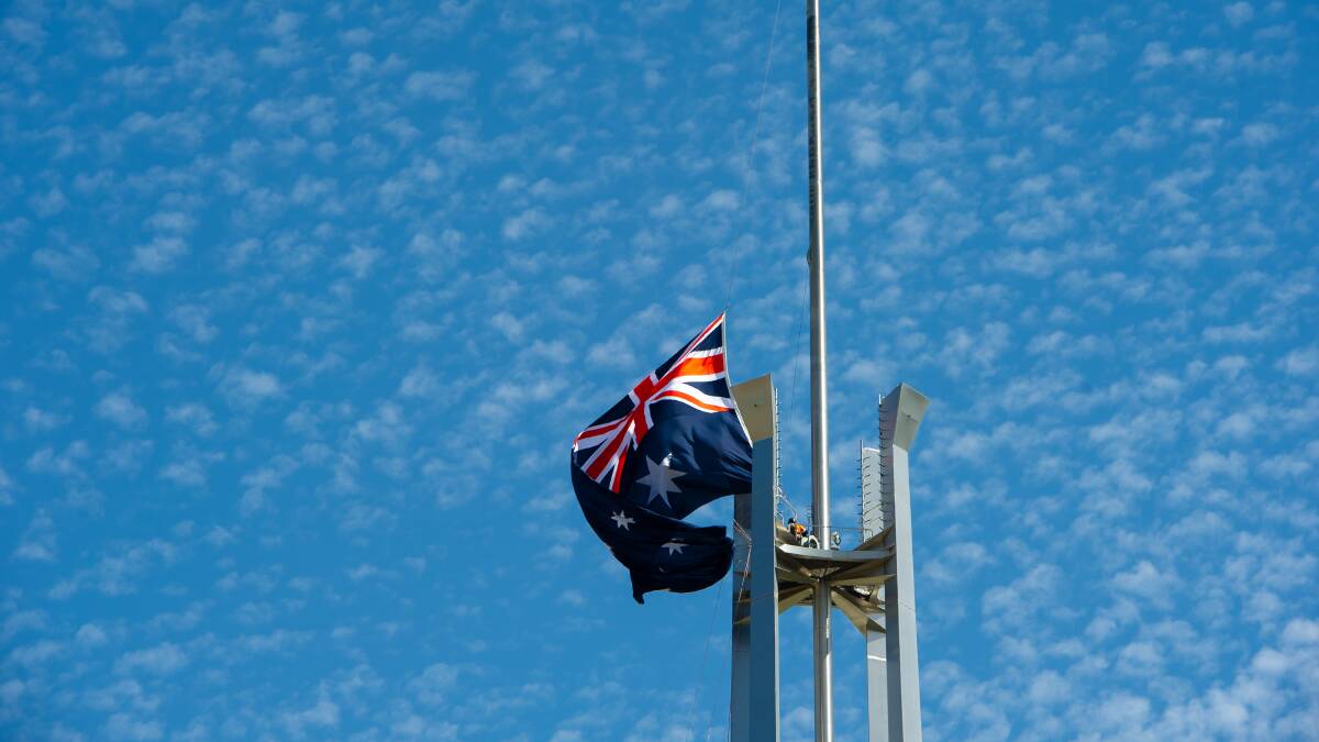 A fresh flag is flown by industrial climbers atop Parliament House. Picture by Elesa Kurtz