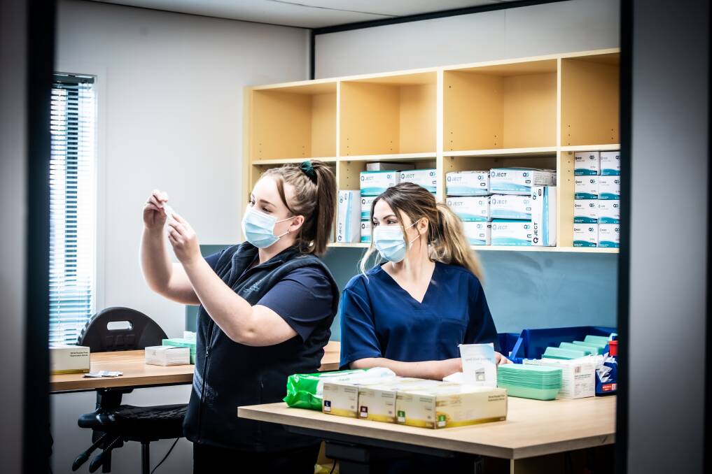 Nurses Felicity Manson and Siobhan Nurmi make sure the Canberra Airport Covid-19 mass vaccination clinic is stocked and ready to operate. Picture: Karleen Minney