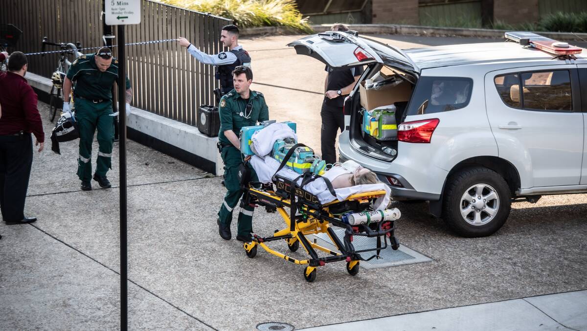 An ambulance officer assisting the victim of an alleged stabbing on the ANU campus. Picture by Karleen Minney.