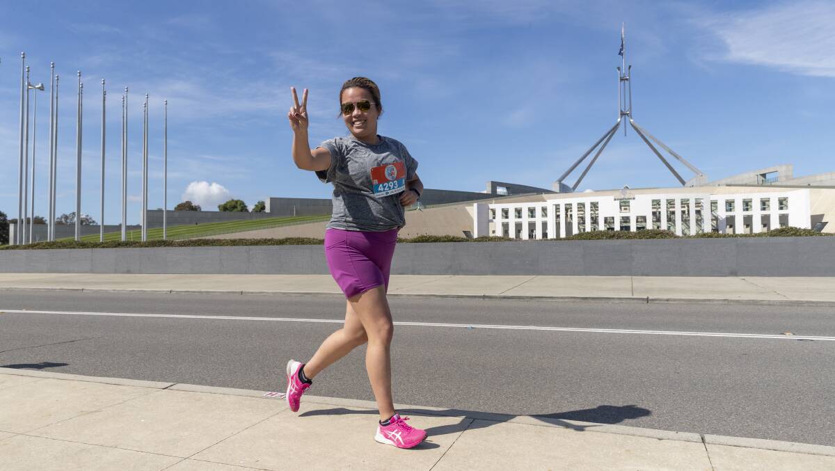 Runner greets our photographer while passing Parliament House. Picture by Keegan Carroll