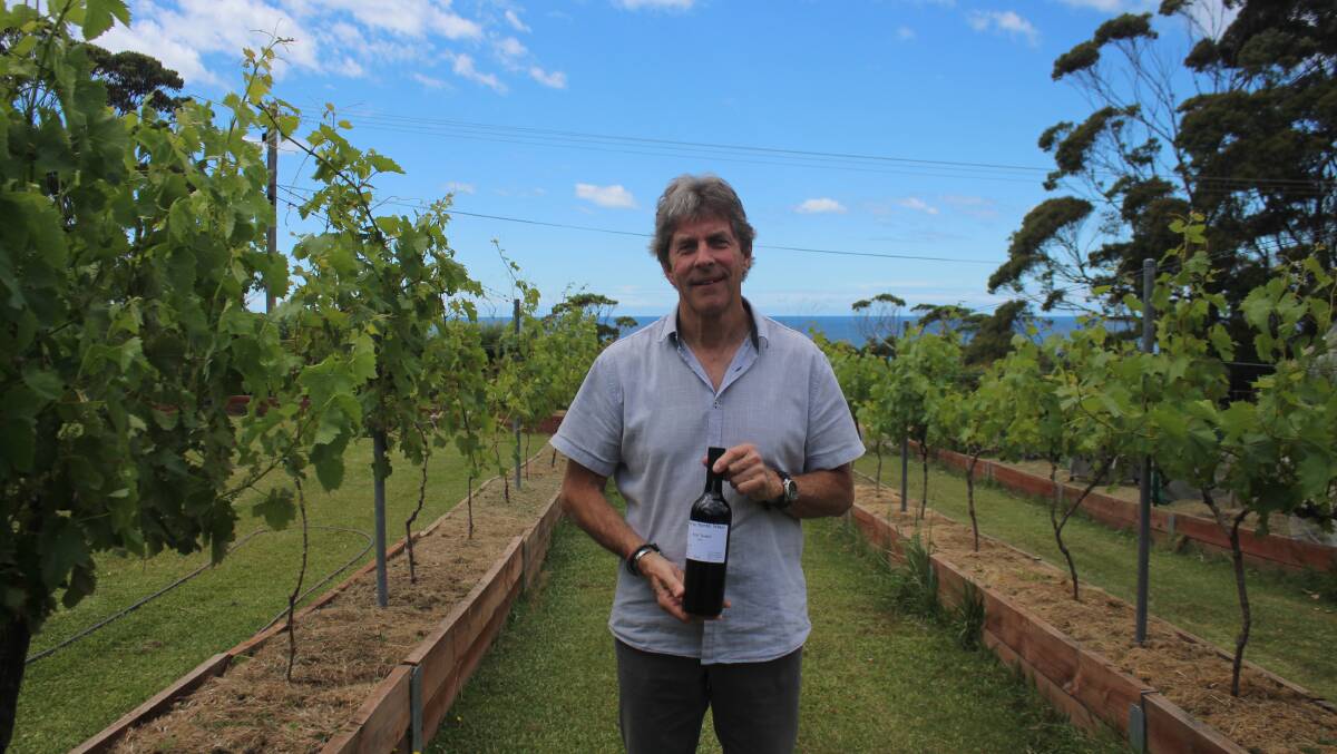 Adrian Farrant in his vineyard with a 2021 bottle of Petit Verdot. Picture by James Tugwell.