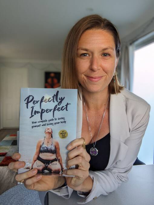 Life coach and author Luna Gaia with her book 'Perfectly Imperfect'. The cover photograph was shot at Sunshine Cove. Picture supplied.
