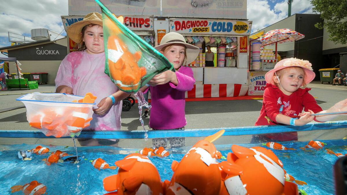 Chloe, 9, Pippa, 7, and Phoebe Wicks, 4, of Richardson, try their hands at the Catch-A-Fish stall. Picture by Sitthixay Ditthavong