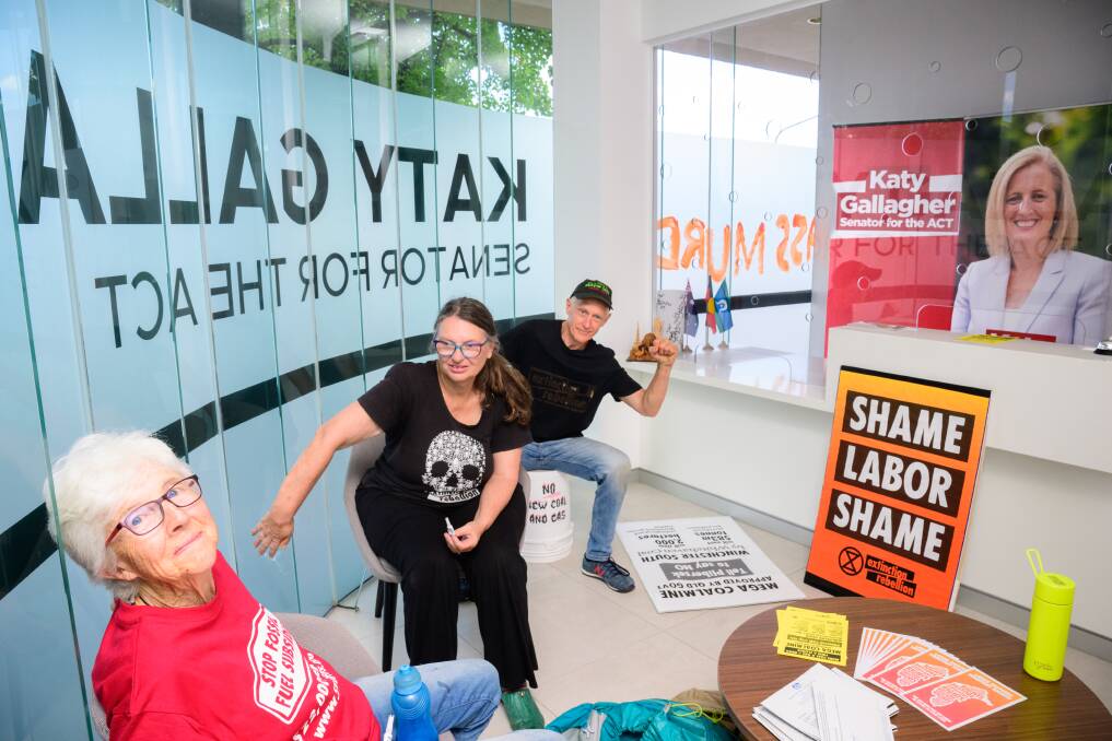 Extinction Rebellion members Margaret Clough, Cate Adams, and John Wurcker glued their hands to the wall while occupying Senator Katy Gallagher's office on Thursday. Picture by Sitthixay Ditthavong 