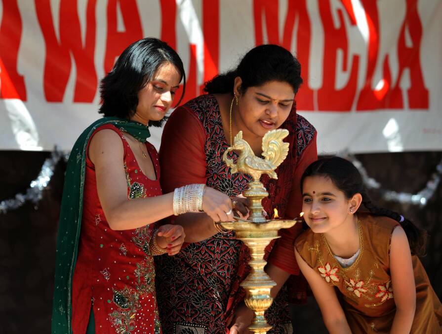 Community members light a lamp at the opening of Diwali Mela, to celebrate Indian festival of lights, at Glebe Park in 2011. Picture by Richard Briggs