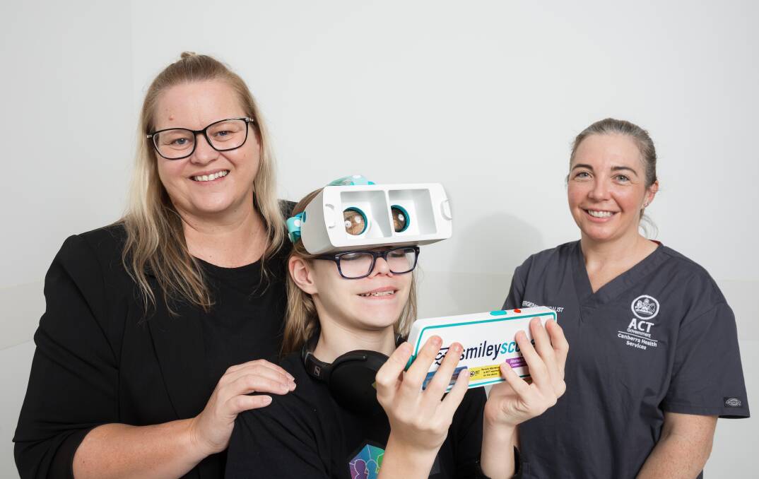 Dr Alison Lally, right, introduces Annabell Fenton and her neurodivergent son Max, 12, to a virtual reality headset at Canberra Hospital. Picture by Sitthixay Ditthavong