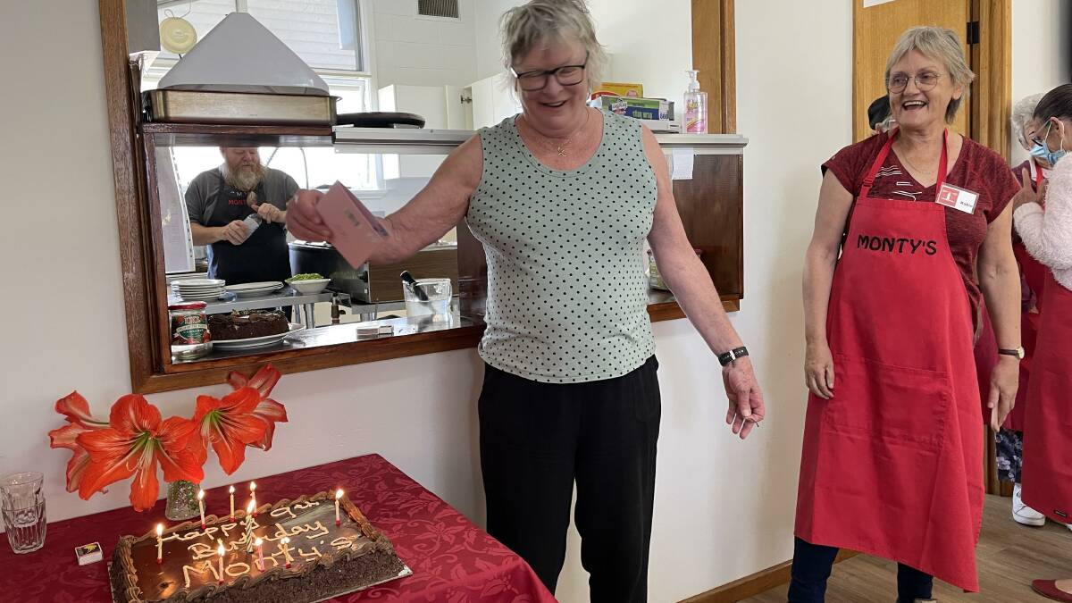 Monty's Place president Di White lights candles on the birthday cake watched on by volunteer Robin Scott-Charlton Picture by Marion Williams