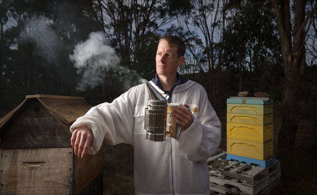 Ben Merivale with two of his beehives and a beehive smoker. Picture by Sitthixay Ditthavong