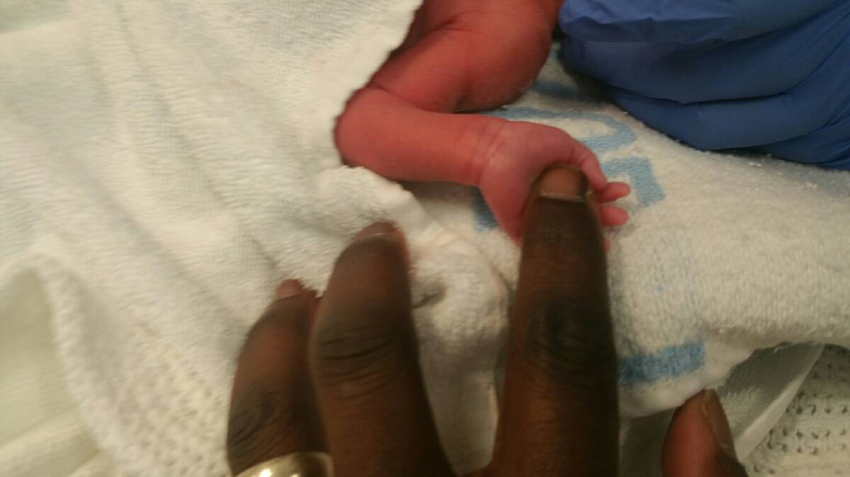 Audrey holds her father Jide's finger at birth. Picture supplied 
