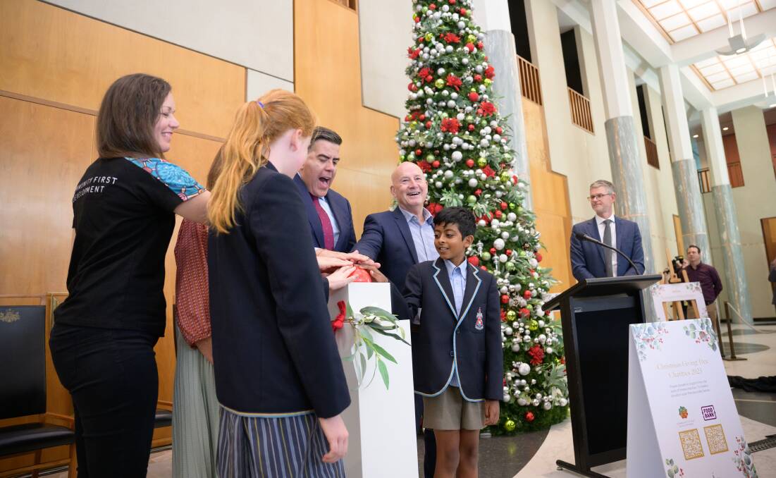 Turning on the lights of the Christmas Giving Tree at Parliament House were Canberra Grammar School students Emily Laverty and Tivon Bandara, Community First Development general manager Sharon Babyack, Senate president Sue Lines, House of Representative Speaker Milton Dick and Foodbank NSW and ACT chief executive John Robertson. Picture by Sitthixay Ditthavong