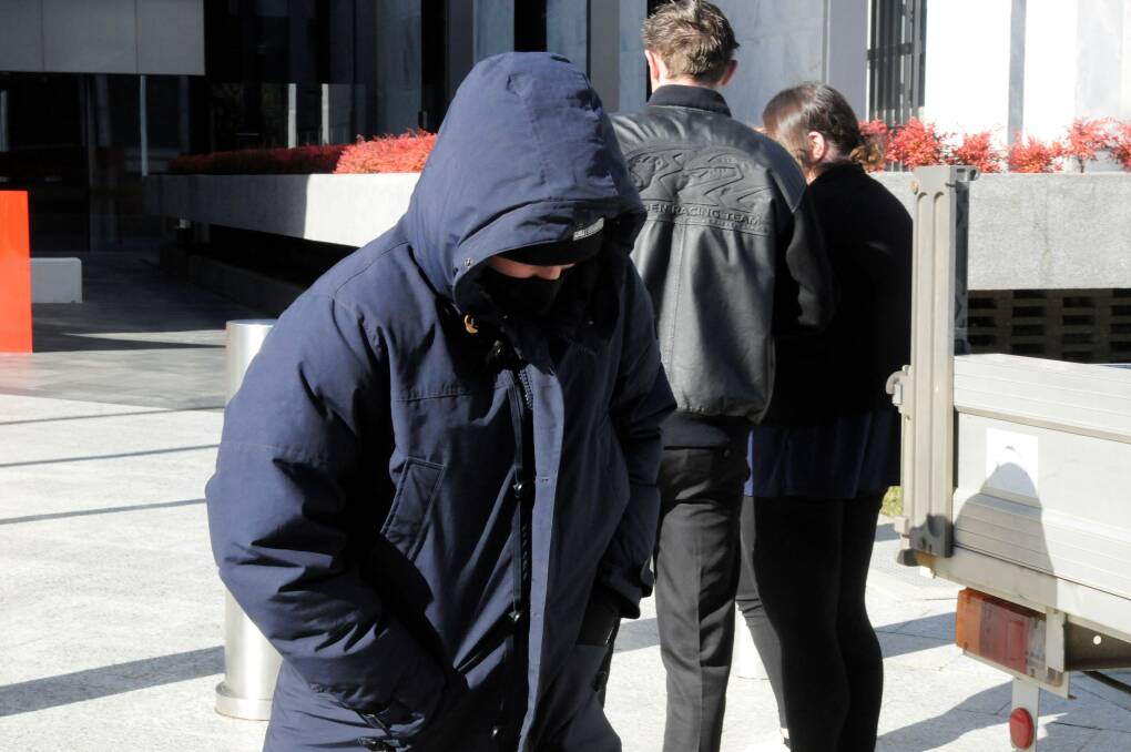 Clinton Dotta scurries away from court with his face hidden. Picture: Blake Foden