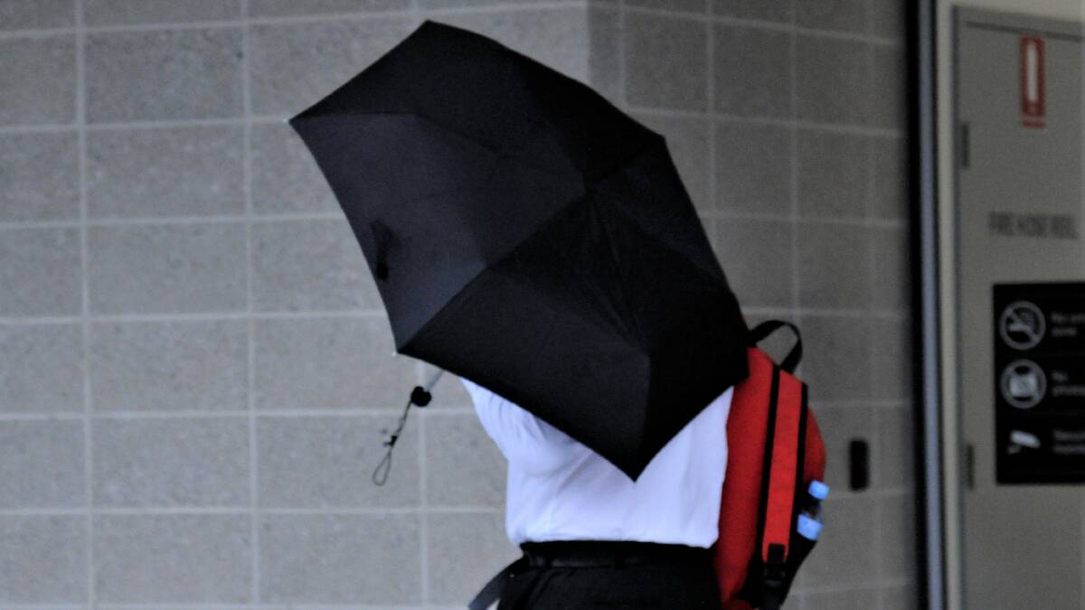 David Horner hides under an umbrella while sprinting from court, having spent hours attempting to avoid being photographed. Picture by Blake Foden