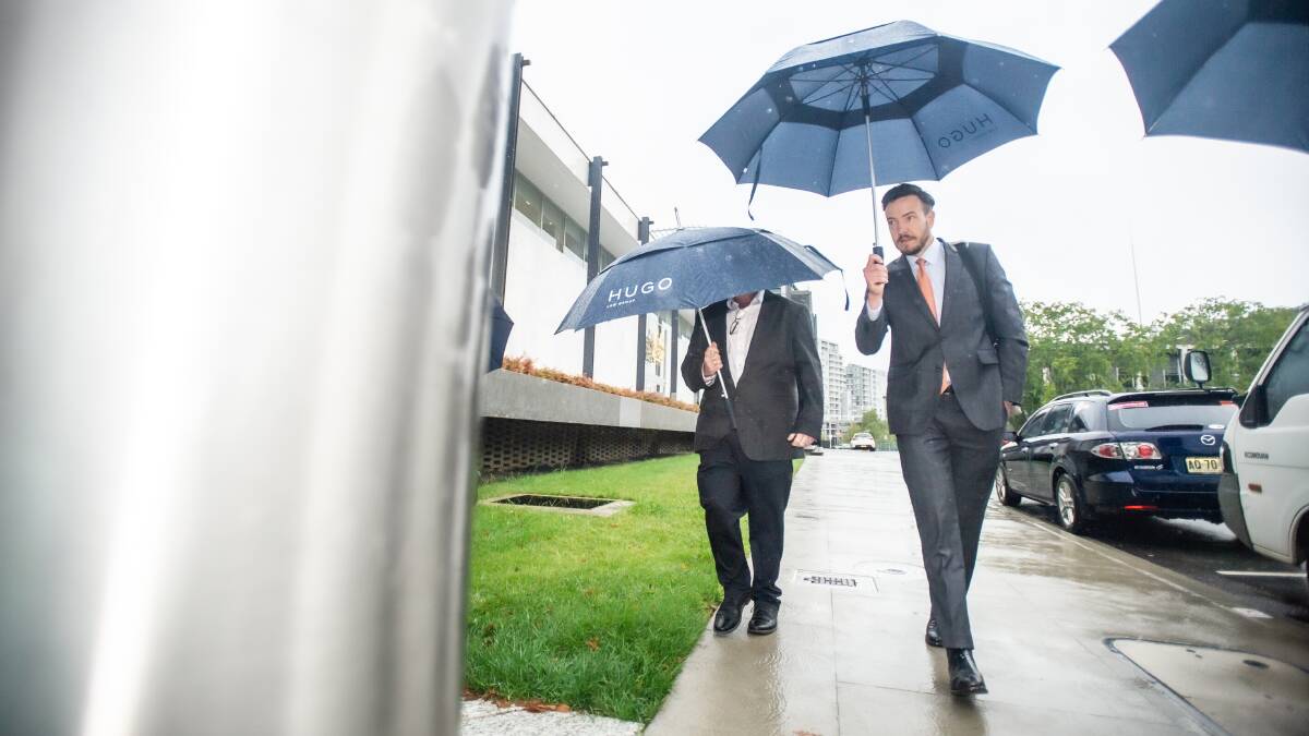 James Mussillon, left, shields his face with a Hugo Law Group umbrella as he arrives at court with solicitor Tom Taylor last month. Picture by Karleen Minney