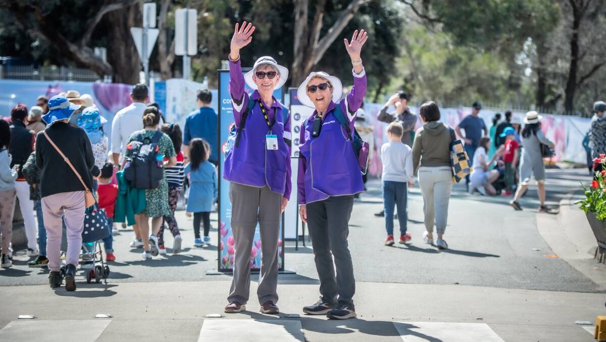 Floriade volunteers and sisters, Janet Anderson, left, and Joy Urquhart, work on the main gate welcoming and advising the thousands of Floriade visitors on a sunny Canberra public holiday. Picture by Karleen Minney