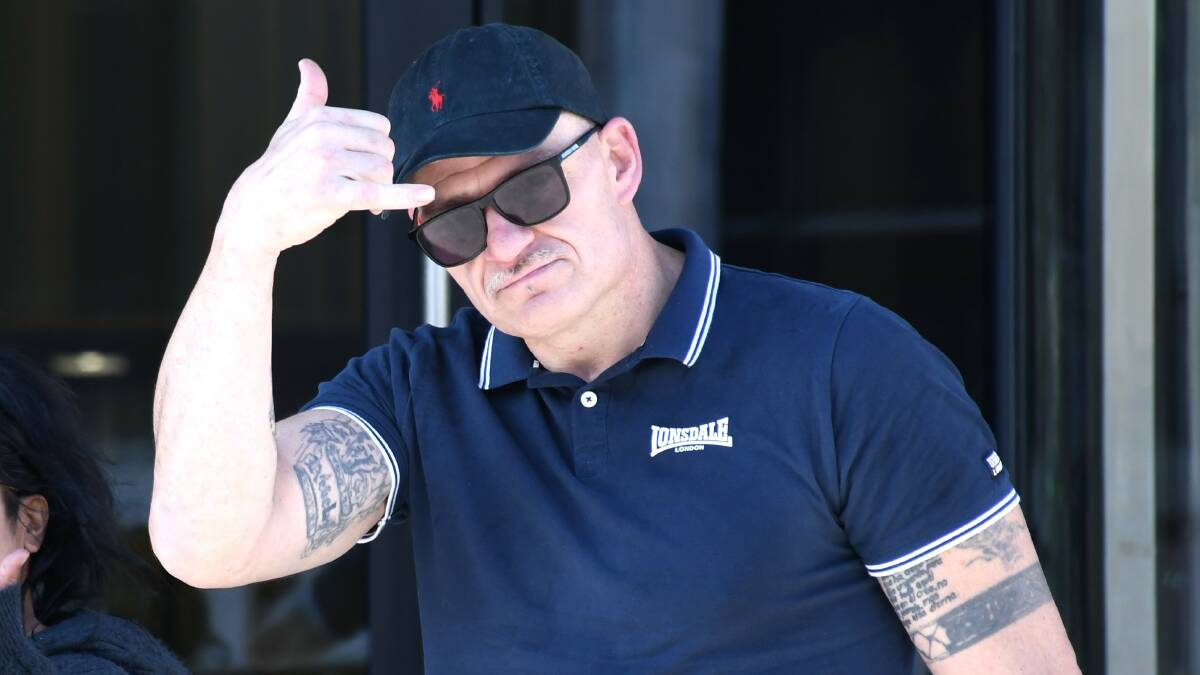 Matthew Massey throws up a 'shaka' hand signal towards reporters outside court on Thursday. Picture by Hannah Neale