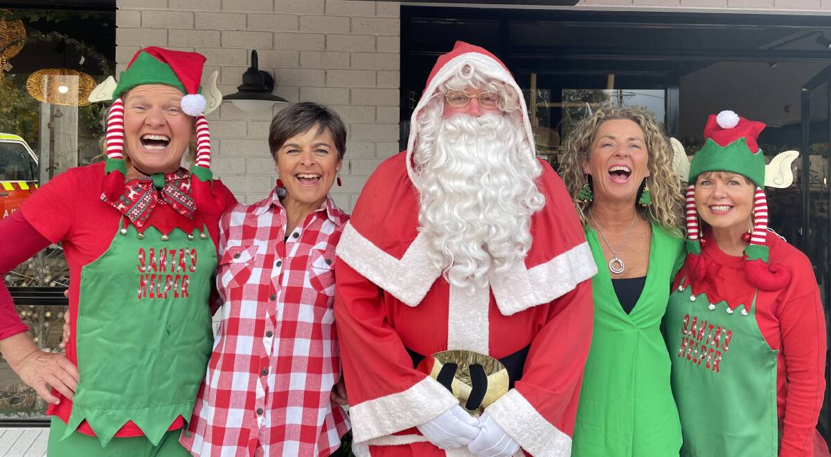 Pambula Business Chamber members Michelle Pettigrove and Michelle Collins of Black Daisy Trading with Santa and his elves.