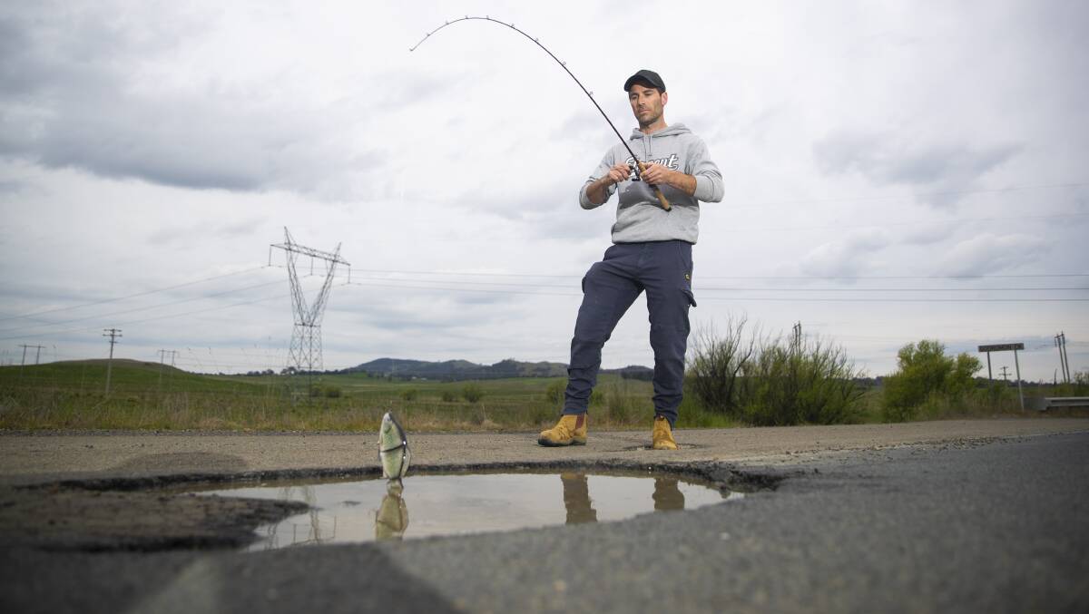 Ben Wilkie from Fraser "fishing" in a pothole on an ACT road. Picture by Keegan Carroll