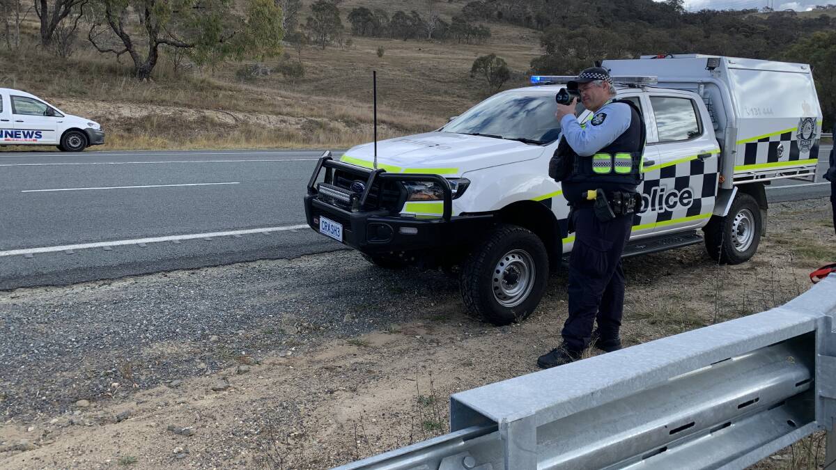 An ACT police officer aims his radar gun down the Monaro Highway. Picture by Peter Brewer
