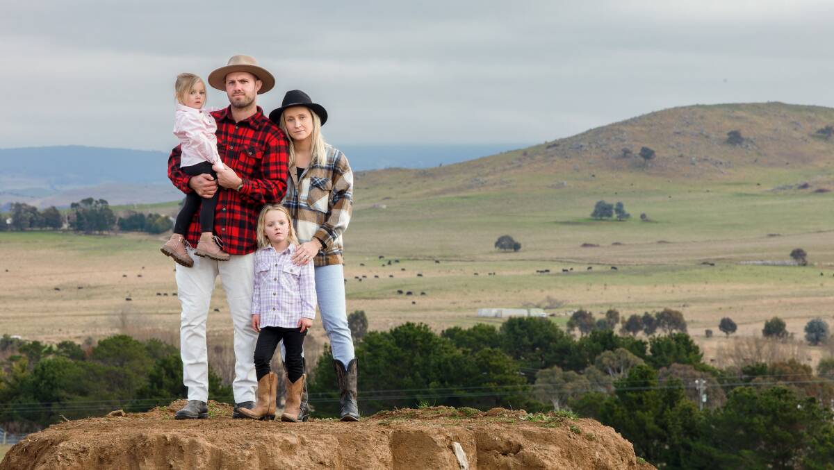 Lachlan and Tash McCaffrey with their daughters Mia, 2, and Harper, 5, at their Wallaroo property. Under the solar proposal, the hill behind them will be coated with solar panels. Picture by Sitthixay Ditthavong