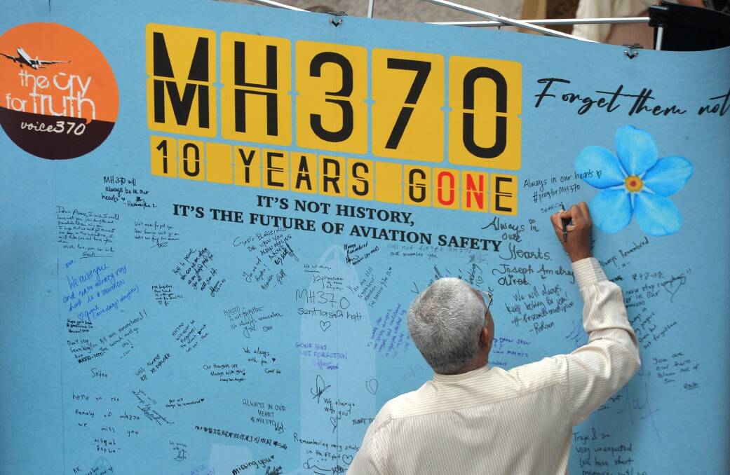 Family members write on a 10-year commemoration board for MH370 in Kuala Lumpur. Picture Shutterstock
