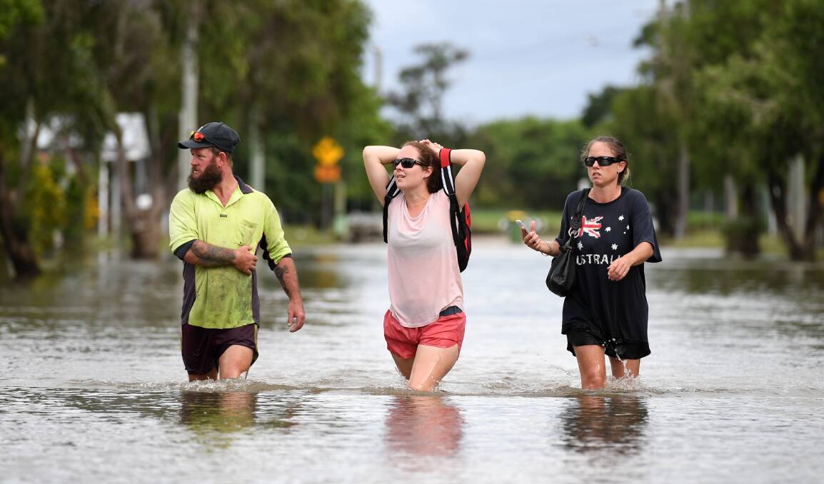 Local residents wade through flood water in Townsville, Queensland, in February this year. Picture: AAP