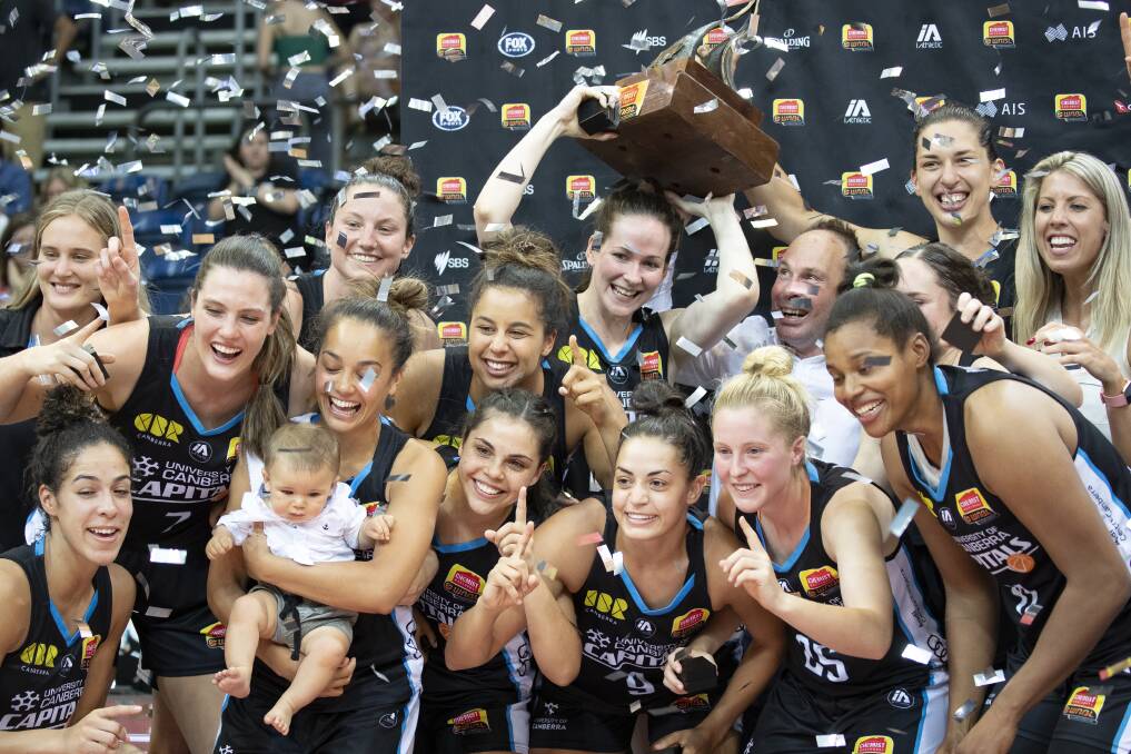 The Canberra Capitals' Kelsey Griffin, Paul Goriss, and Marianna Tolo hoist the WNBL championship trophy. Picture: Sitthixay Ditthavong