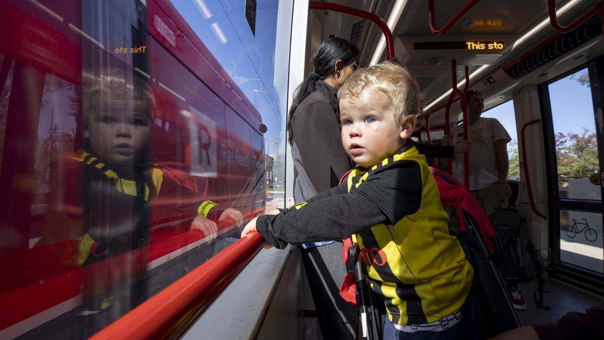 Twenty-month-old Christian Grive from Waniassa stares out the window as another light rail vehicle rushes past on the opening day of operations for the Canberra light rail. Photo: Sitthixay Ditthavong