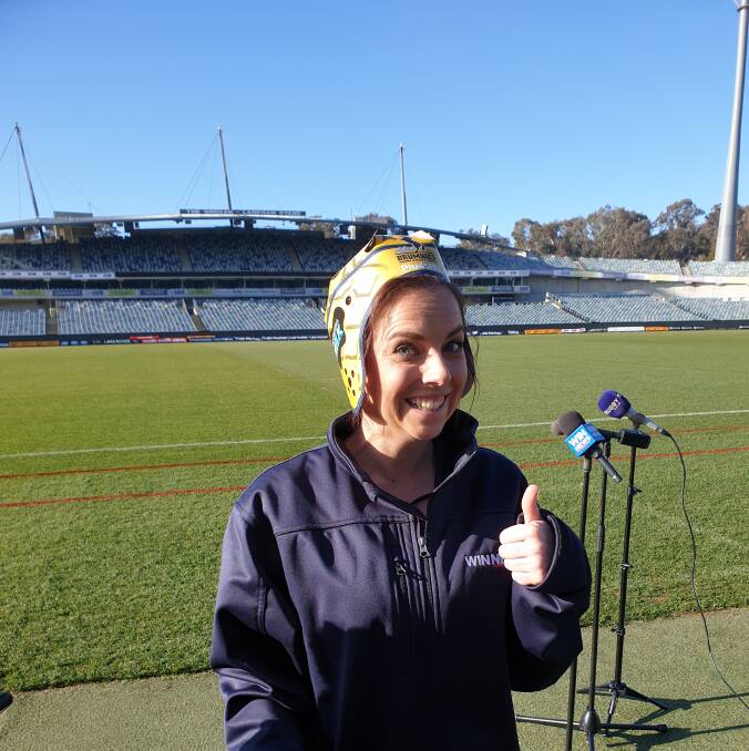 WIN News sports reporter Caitlyn Chalmers models the headgear that will be handed out at Saturday's Brumbies game.