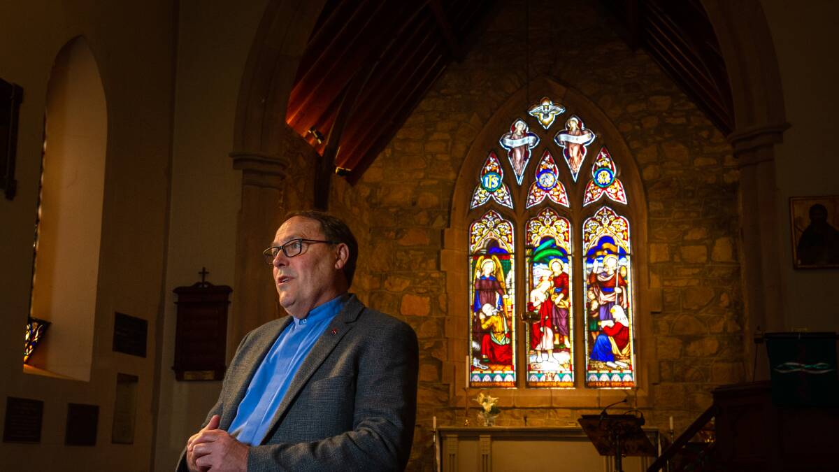 St John's Anglican Church rector Father Paul Black, with the church's main stained-glass window installed in 1874. Picture: Elesa Kurtz