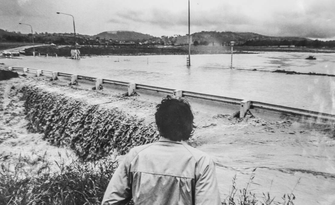 A passerby inspects the flooded Yarra Glen intersection after the Woden floods in 1972. Picture Canberra Times archive