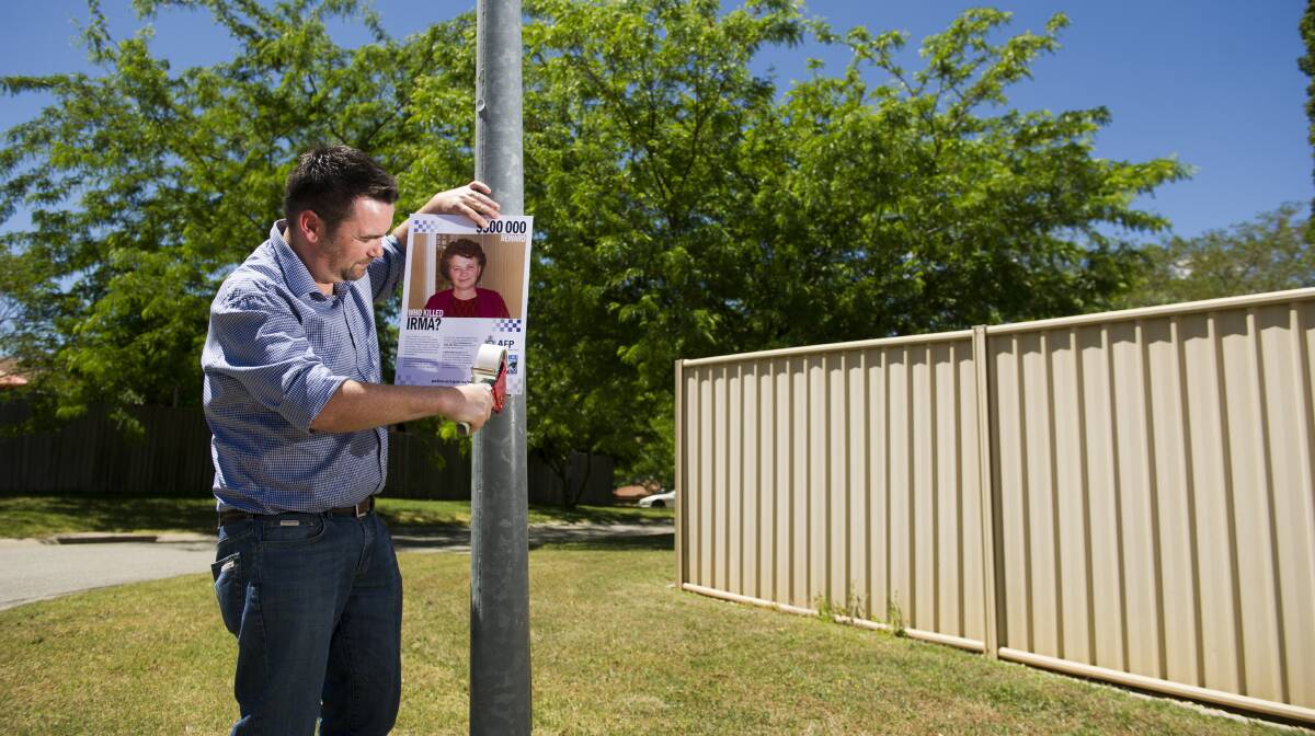 John Mitika putting up posters around Canberra to remind and encourage people to come forward with information on the murder of this grandmother Irma Palasics. Picture by Jay Cronan