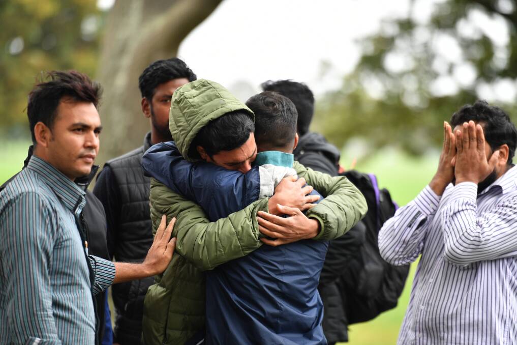 Friends of a missing man grieve outside a refuge centre in Christchurch. Photo: AAP