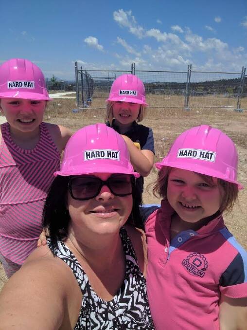 Lizzie Christiansen on the site of her new home at Denman Prospect with daughters Freyja (front) and Brynn and Inge. The family may lose the home as Ms Christiansen cares for Freyja, who has a rare form of cancer. Photo: Supplied
