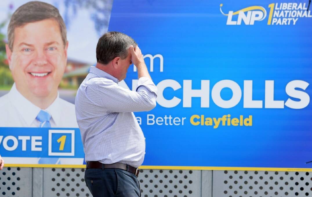 Queensland Opposition Leader Tim Nicholls walks past one of his signs on the last day of the campaign. Photo: Tracey Nearmy