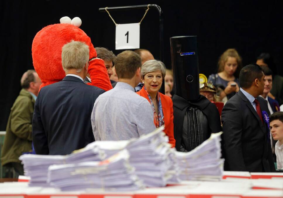 Theresa May stands next to candidate 'Lord Buckethead' and Elmo as she waits for the declaration at her constituency. Photo: Alastair Grant