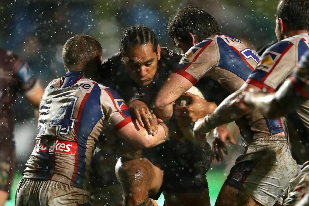 Wet and wild: Martin Taupau drives into the Newcastle defence on Friday night. Photo: Getty Images