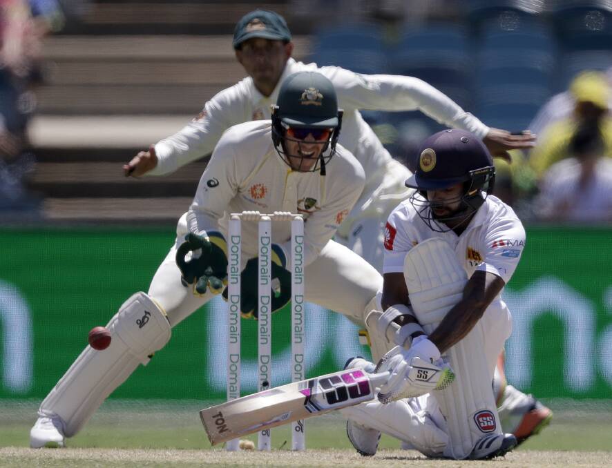 Dilruwan Perera sweeps in front of Tim Paine at Manuka Oval. Photo: AP