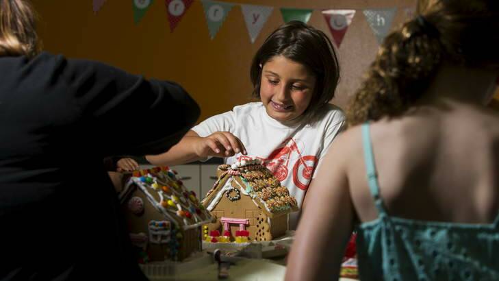 Faith Carcavelos, 10, puts the final touches on her gingerbread house at the Belconnen fresh food markets on Sunday. Photo: Rohan Thomson