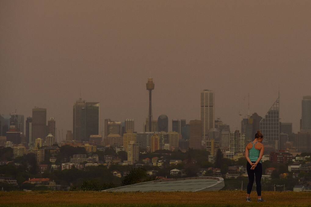 Dust fills the air as a woman stands at Dudley Page Reserve in Dover Heights, Sydney. Photo: Sydney Morning Herald