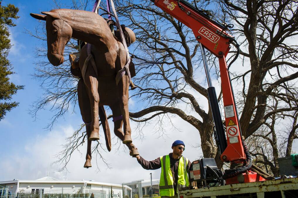 Exhibition production officer Yuri Humeniuk installs Andy Townsend and Suzie Bleach's sculpture 'A Burden' on the Floriade grounds.  Photo: Sitthixay Ditthavong