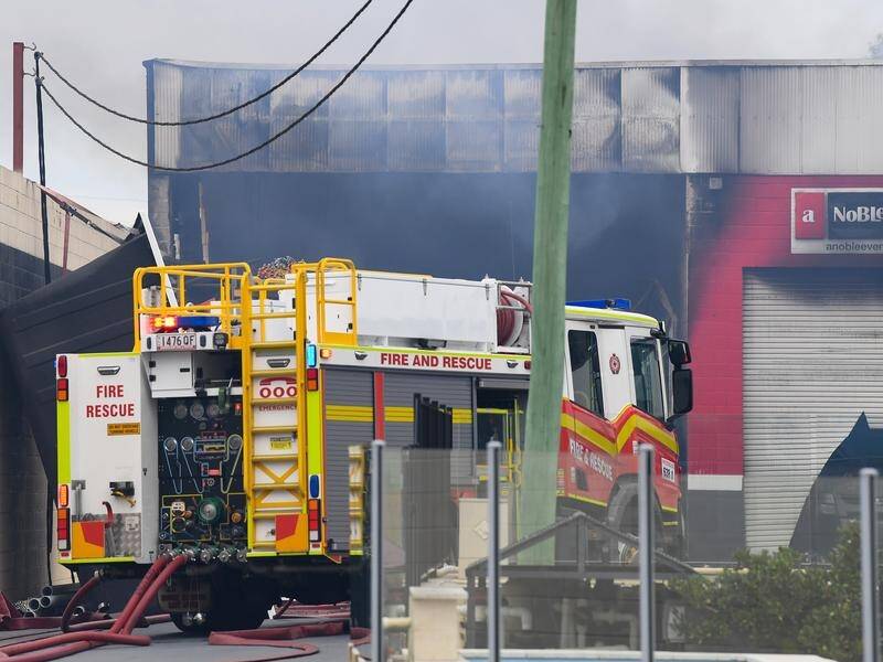 Firefighters have worked through the early hours of the morning to contain a Brisbane factory fire. (Jono Searle/AAP PHOTOS)